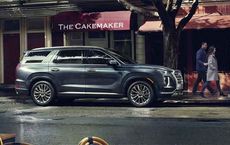 Large SUV parked on a city street outside a bakery, reflecting on a rainy day, featured on digipdemo.com.