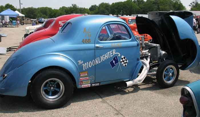 Vintage blue car at an auto show, showcasing engine modifications for alternative fuels, featured on digipdemo.com.
