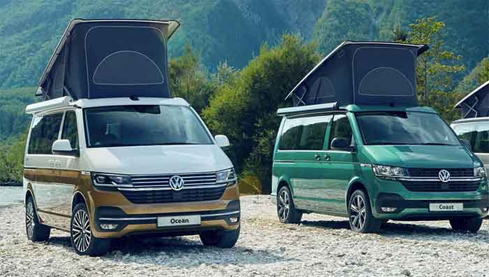 Two camper vans with pop-up roofs parked in a scenic mountain area, ideal for outdoor adventures.