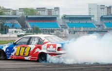"Car performing a high-speed drift on a racetrack, producing a cloud of smoke, at a drifting event on digipdemo.com."